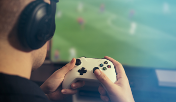 A man engrossed in a video game. Man holding gamepad and playing soccer game